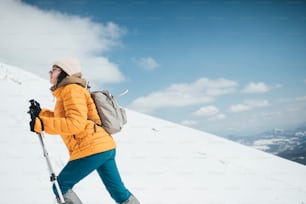 Young woman climbing mountain using hiking poles.