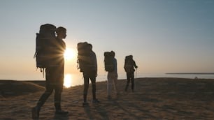 Los cuatro viajeros con mochilas caminando hacia la orilla del mar