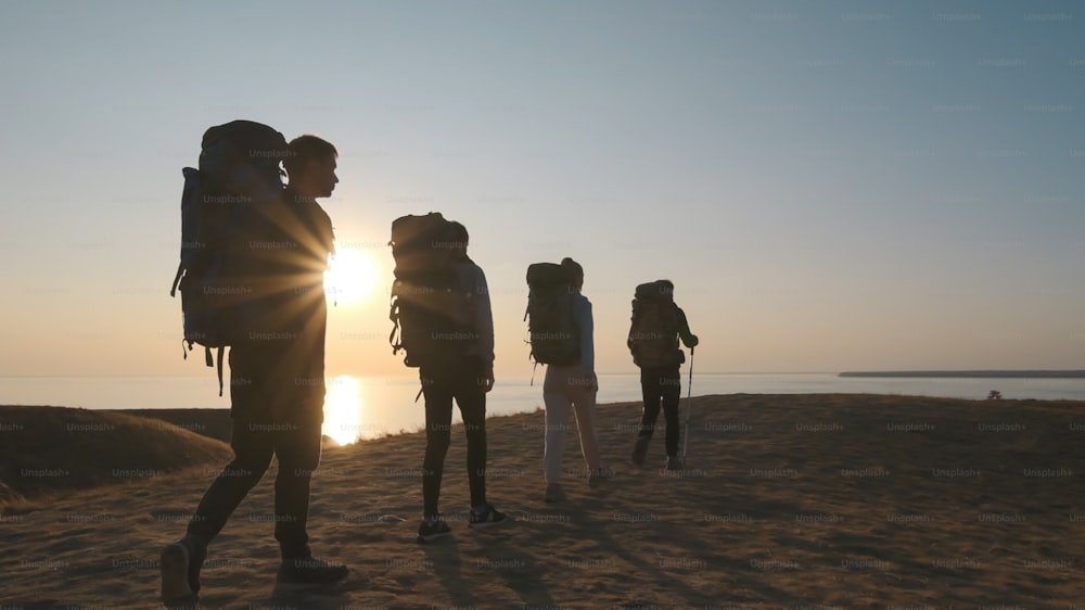 The four travelers with backpacks walking to the sea shore