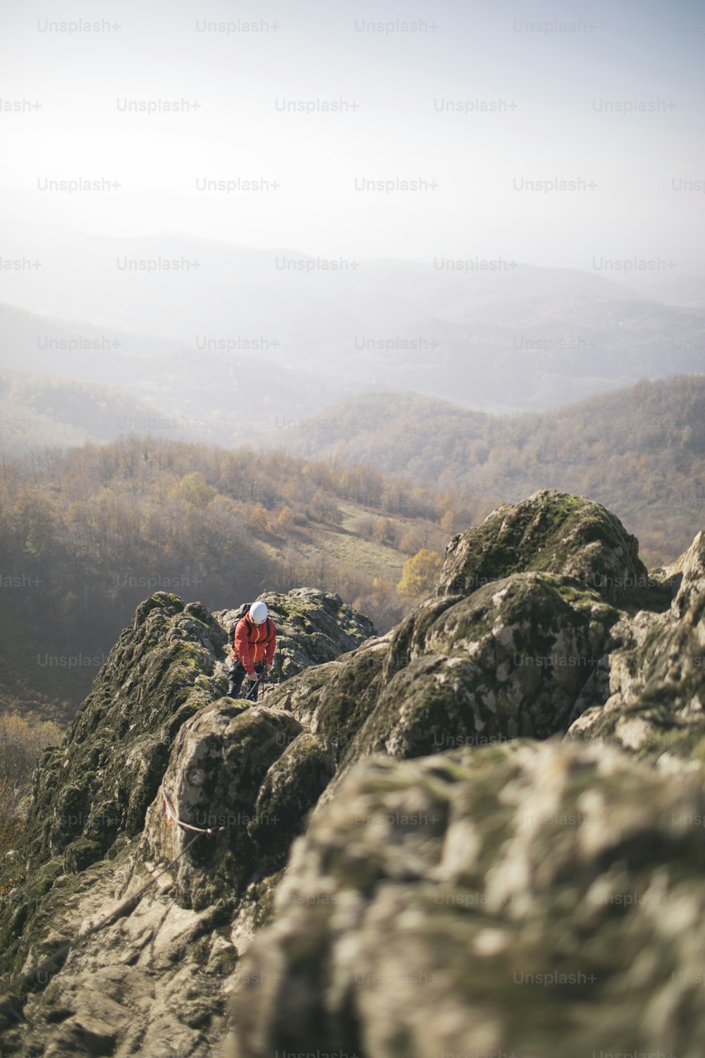 Hombre totalmente equipado escalando montaña a lo largo de una vía ferrata.