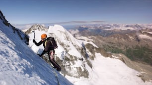 male mountain climber on a high alpine glacier with a great view of the fantastic mountain landscape of the Engadin Valley behind him