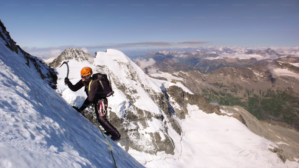 male mountain climber on a high alpine glacier with a great view of the fantastic mountain landscape of the Engadin Valley behind him