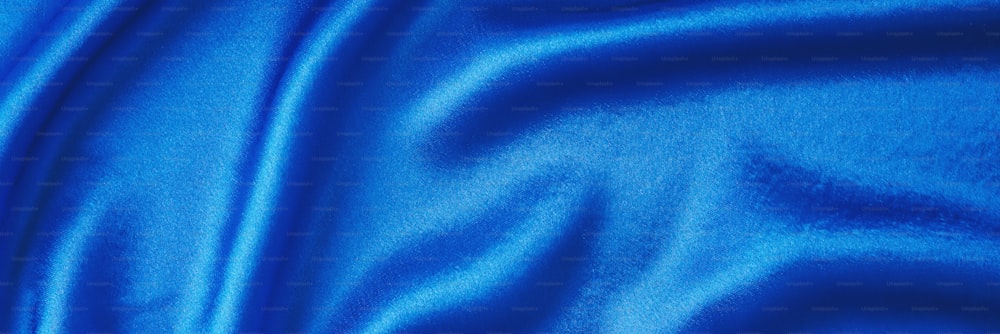 Fondo di seta blu con pieghe.  Trama astratta della superficie satinata increspata, banner lungo