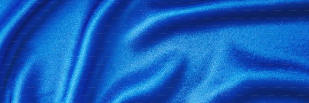 Blue silk background with folds.  Abstract texture of rippled satin surface, long banner