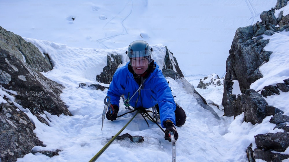 male ice climber near the end of a steep ice fall in the Alps