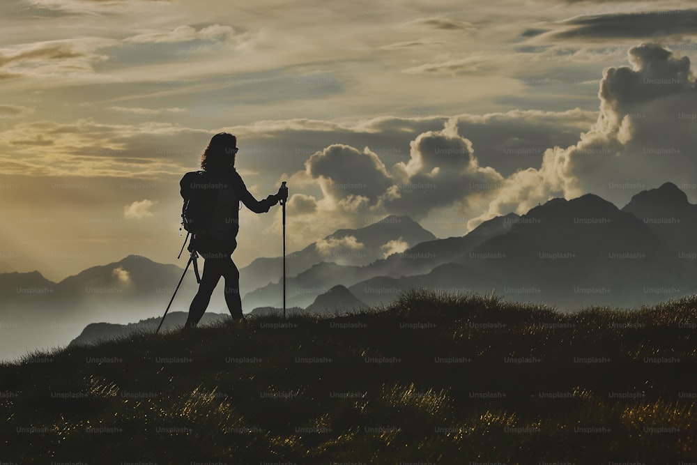 Caminhe na solidão nos Alpes. Uma mulher com o fundo de montanhas abstratas nas nuvens.