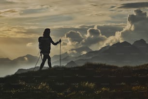 Walk in solitude on the Alps. A woman on with the background of abstract mountains in the clouds.
