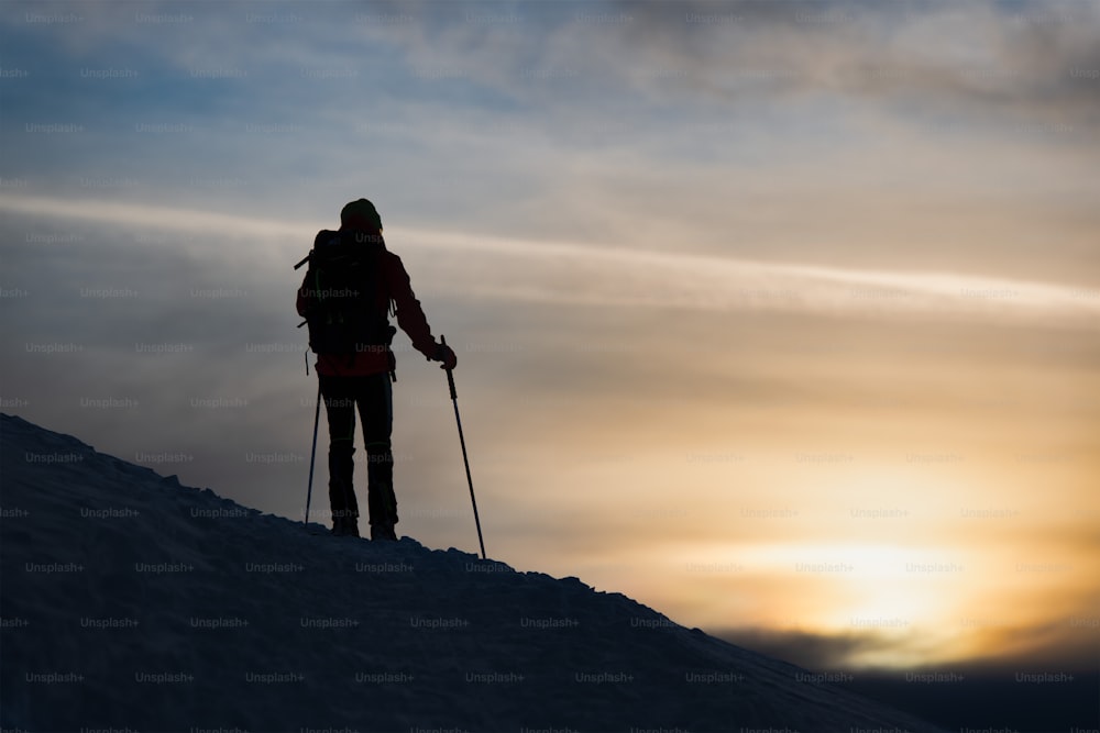 A mountaineer skier watches the sun go down