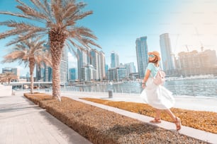 Chica asiática feliz caminando en un paseo marítimo en el distrito de Dubai Marina. Viajes y estilo de vida en Emiratos Árabes Unidos
