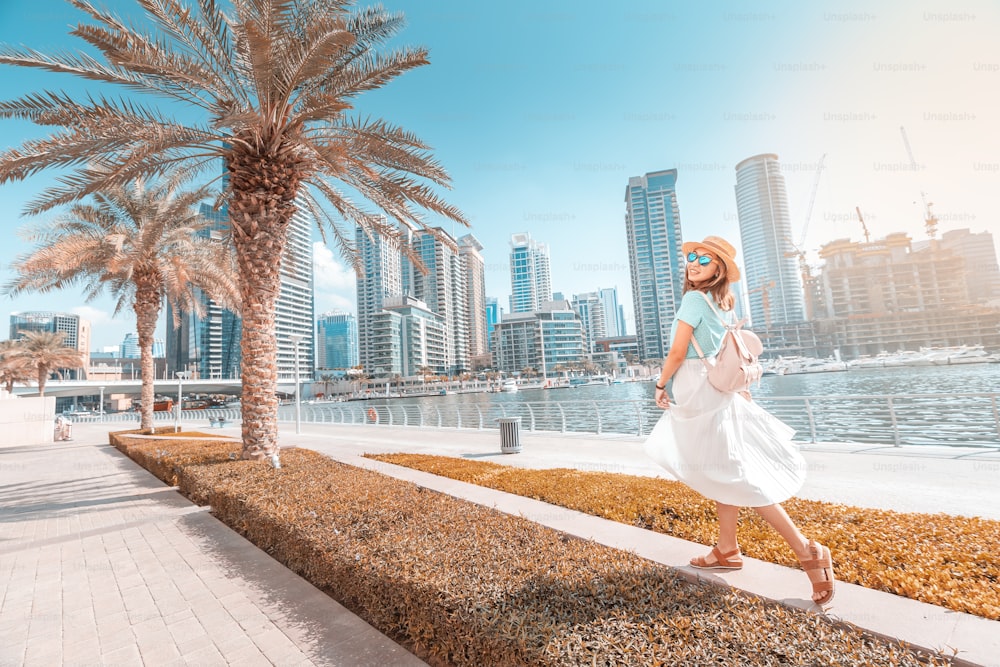 두바이 마리나 지구의 산책로를 걷고 있는 행복한 아시아 소녀. 아랍에미리트의 여행과 생활