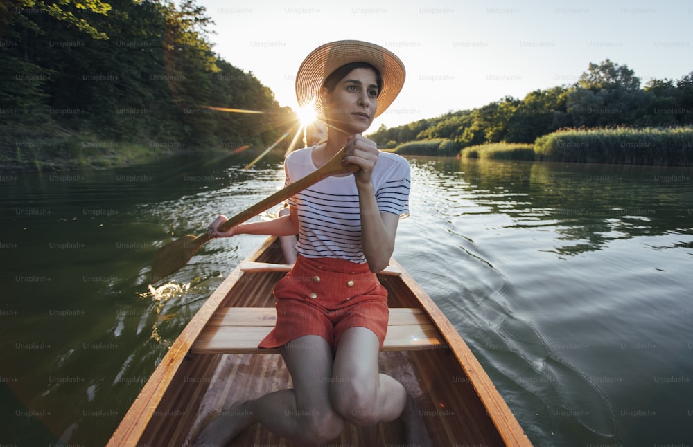 O casal gosta de remar de canoa no lago do pôr do sol. Mulher e homem em um passeio de barco de lazer.