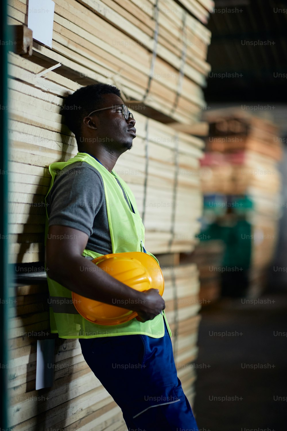 Pensive African American warehouse worker taking a break after hard working day at wood department.