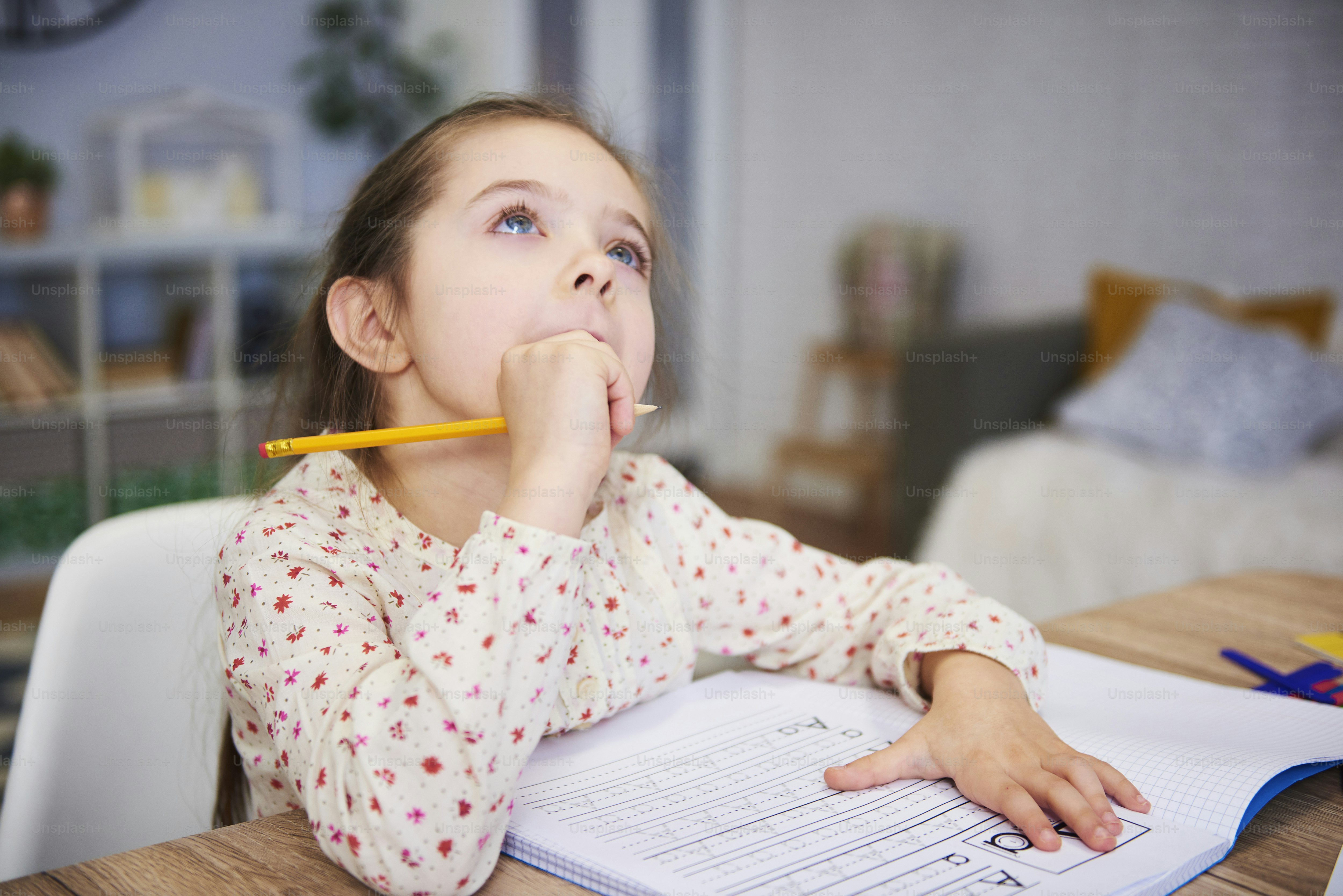 School-aged child showing child eye exam signs while reading homework at a desk