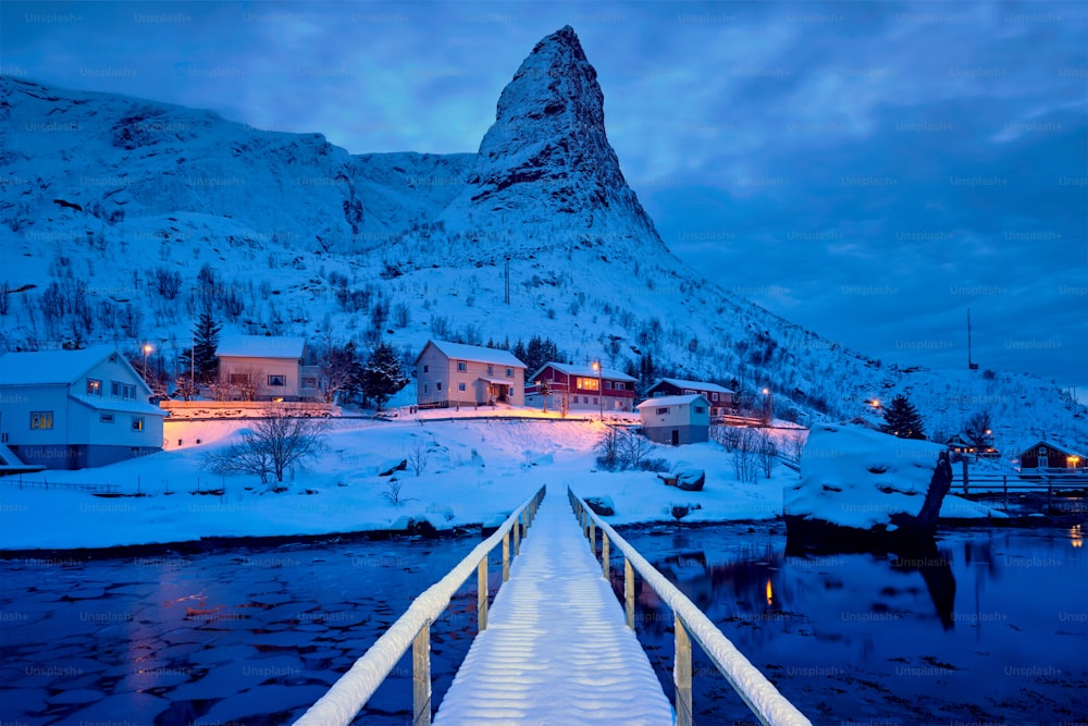 Ponte nel villaggio di Reine coperto di neve di notte. Isole Lofoten, Norvegia