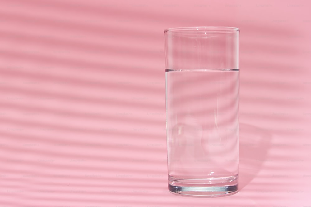 ピンクの背景にコップ一杯の水
