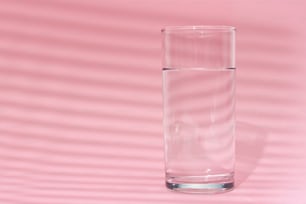Bicchiere d'acqua su sfondo rosa