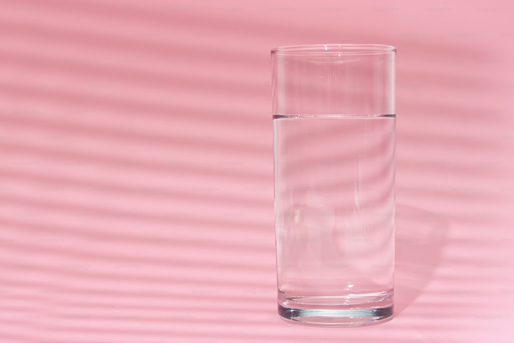 Glass of water on pink background