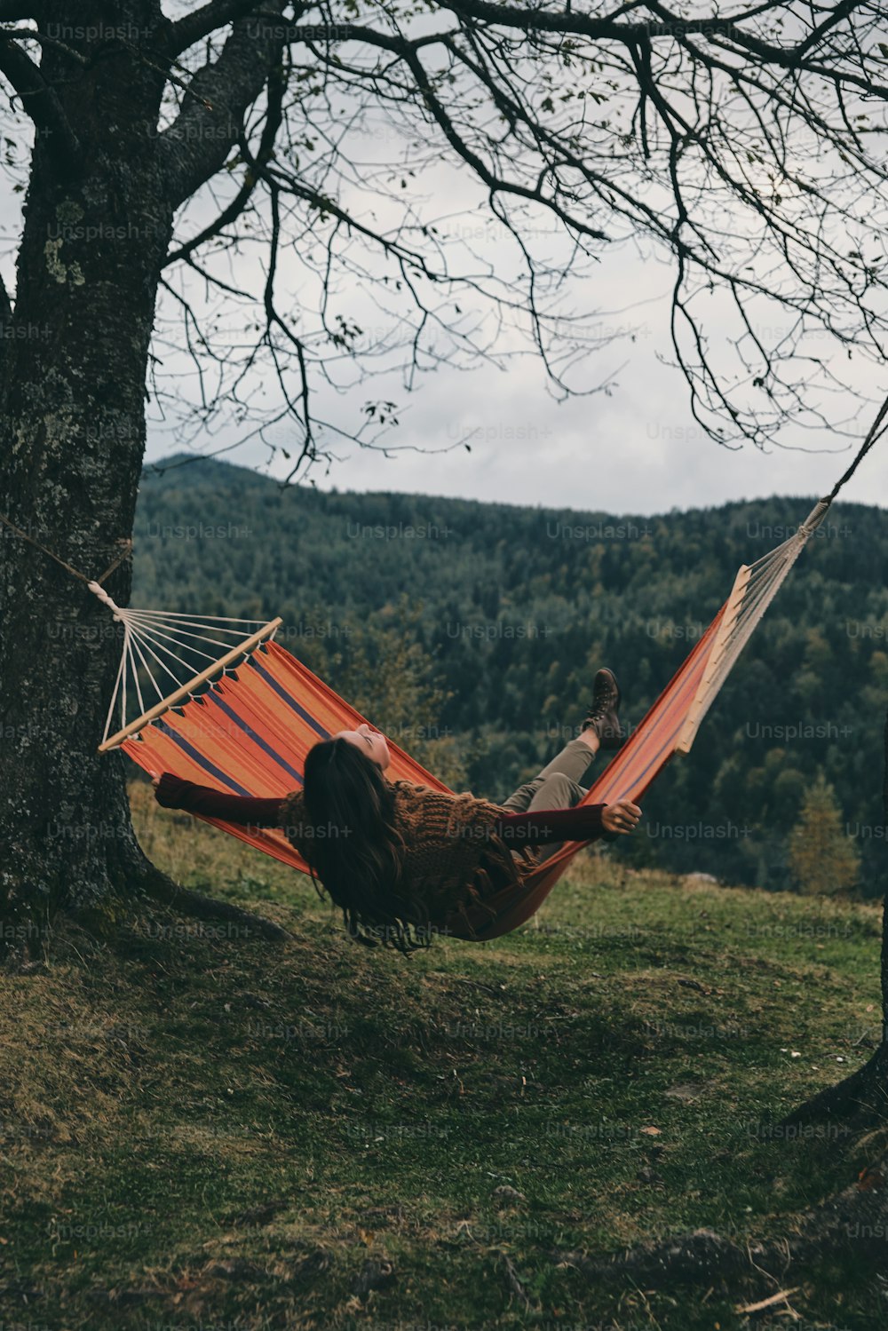 Beautiful young woman lying in hammock while relaxing on the valley under the tree