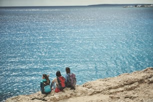 Paysage magnifique. Des voyageuses paisibles se détendent sur une falaise près de l’eau. Ils regardent l’océan infini avec admiration