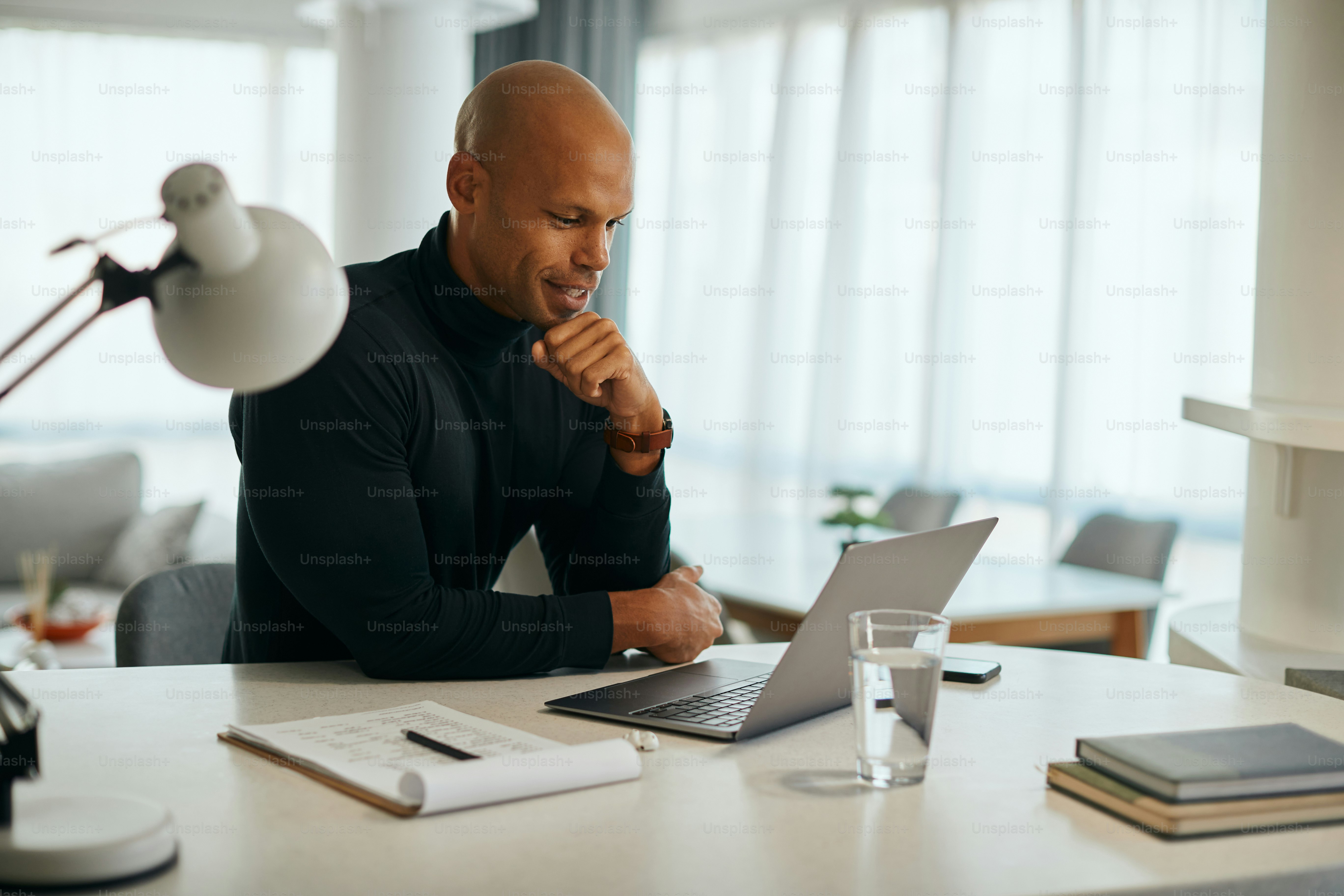 Young African American businessman using laptop while working at home office.