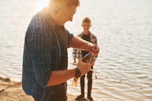Concepção de hobbies. Pai e filho pescando juntos ao ar livre no verão.