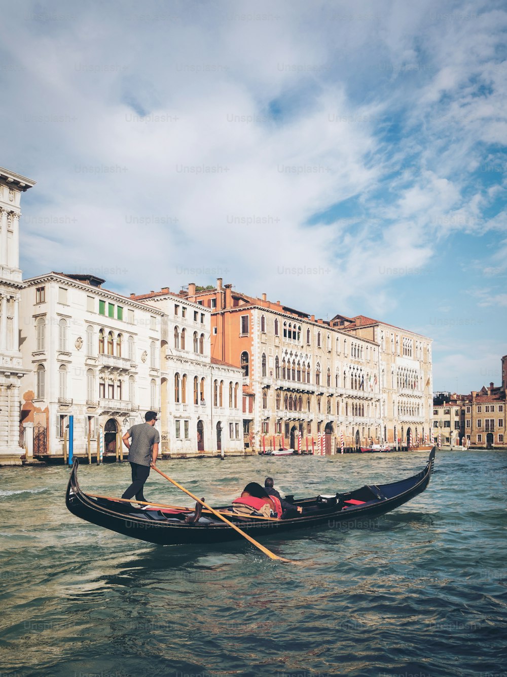 Venetian gondolier punting gondola through grand canal of Venice, Italy. Gondola is a traditional, flat-bottomed Venetian rowing boat. It is the unique transportation of Venice, Italy.