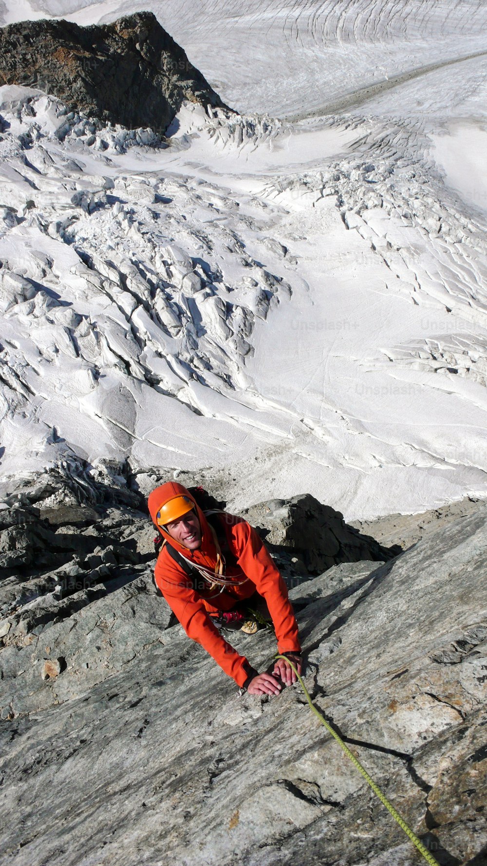 male mountain climber on an exposed climbing route high above a glacier in the Swiss Alps near St. Moritz