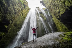 Viajante atordoado pela cascata da cachoeira Gljufrabui na Islândia. Localizado na pitoresca cachoeira Seljalandsfoss ao sul da Islândia, Europa. É o principal destino bonito de atração de viagem turística popular.