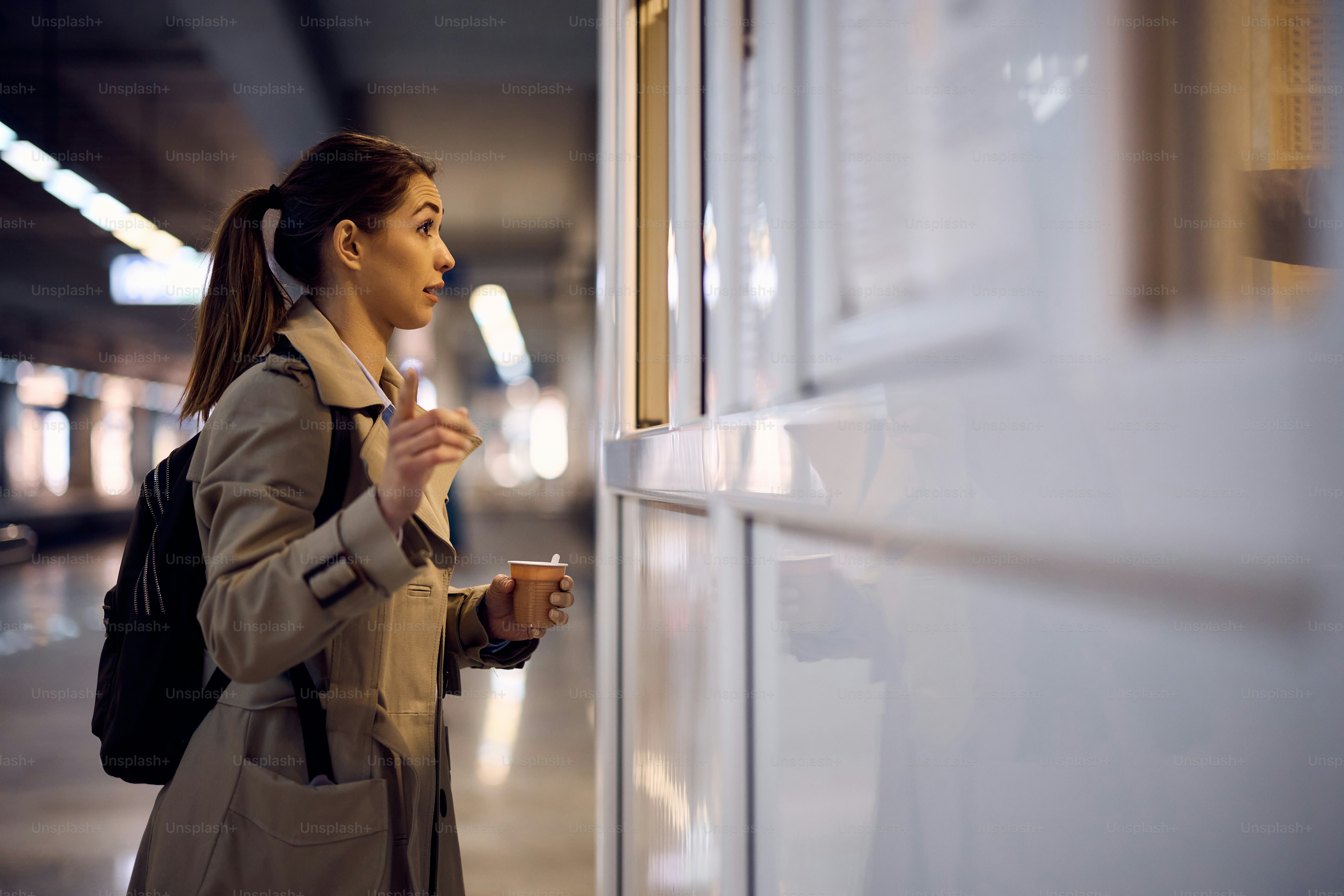 Female tourist talking to someone at information booth at railroad station.