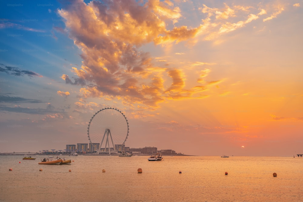 有名なドバイ・アイ観覧車のあるブルーウォーターズ島に沈む赤い夕日。UAEの街と自然のパノラマビュー