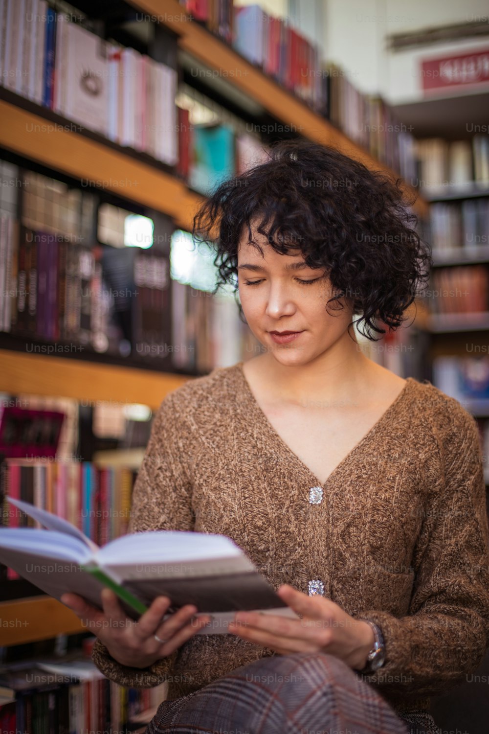 Girl in library reading book.