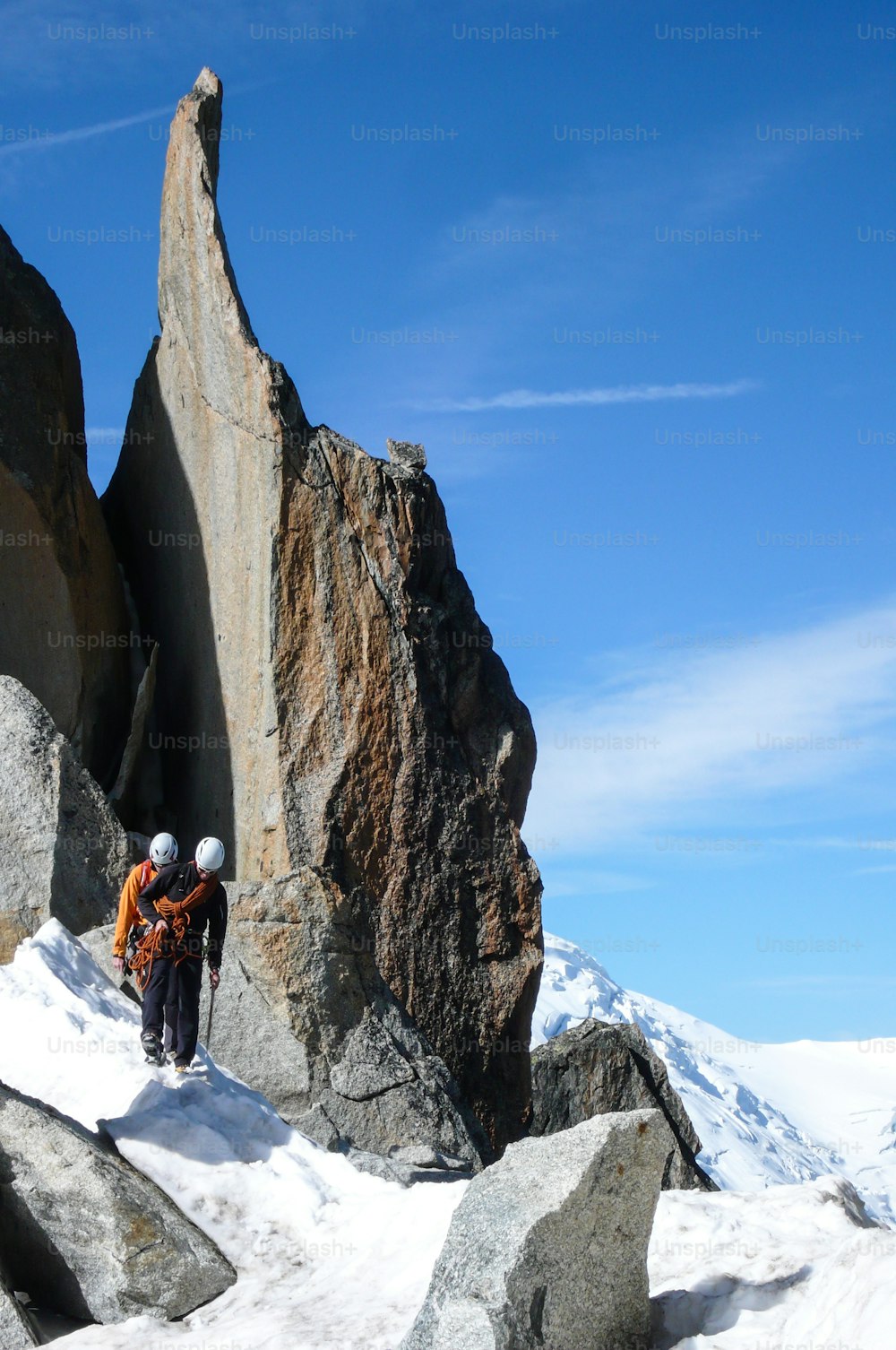 guía de montaña y un cliente masculino en una cresta rocosa que se dirige hacia una alta cumbre en los Alpes franceses cerca de Chamonix en un hermoso día de verano