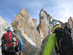 Un guide de montagne et un client masculin sur une crête rocheuse en direction d’un haut sommet des Alpes françaises près de Chamonix
