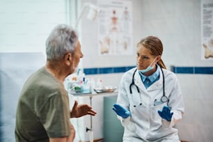 Female doctor talking to senior patient during medical exam at the clinic.