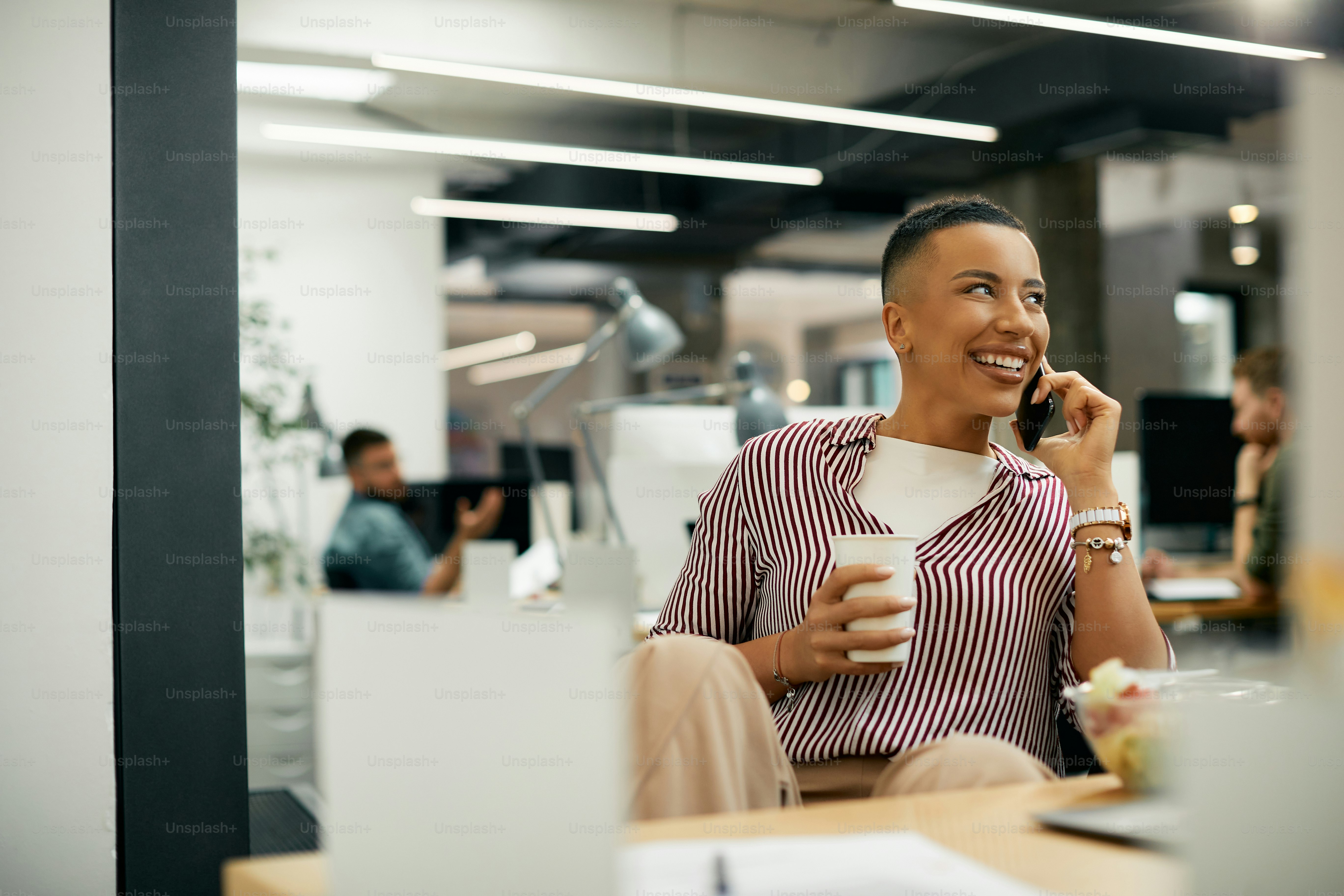 Pekerja lepas wanita Afrika-Amerika yang bahagia berkomunikasi di ponsel sambil beristirahat dari pekerjaan di kantor.