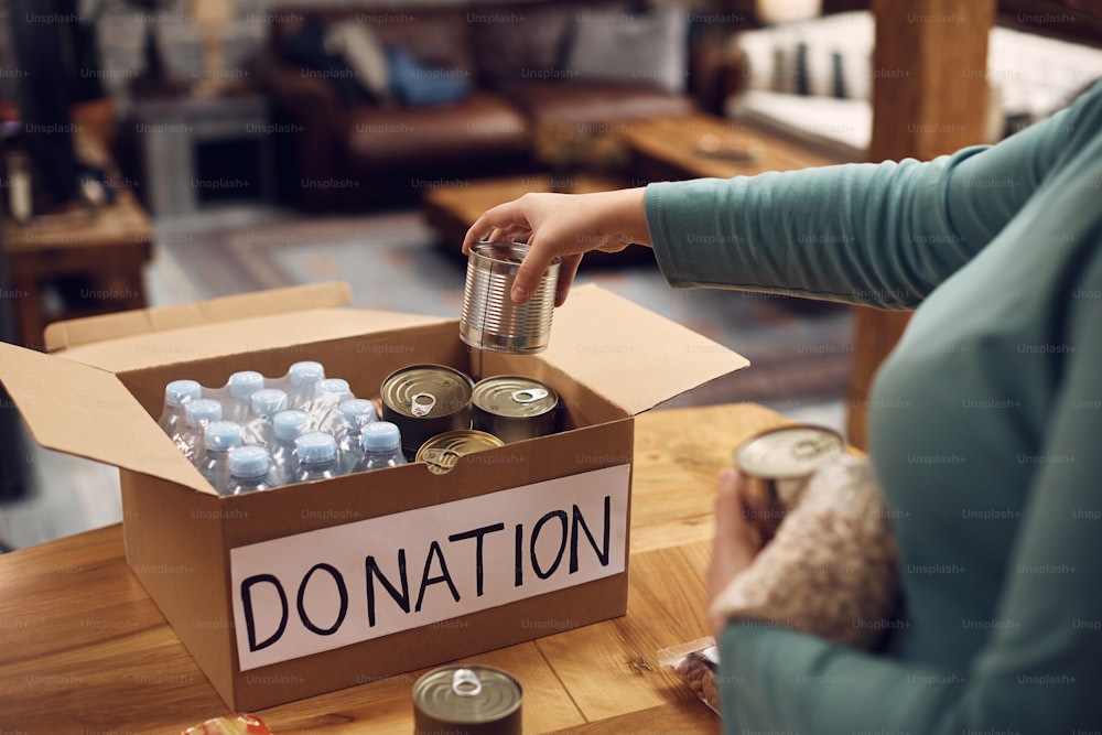 Close-up of woman preparing donation box for charitable food bank.