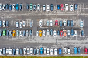 Aerial view from above of the parking lot with cars in the business district of the city, wet asphalt