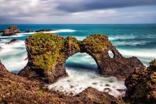 Amazing stone arch Gatklettur basalt rock on Atlantic coast of Arnarstapi in Iceland. The famous natural form arch attracts tourist to visit west of Iceland.