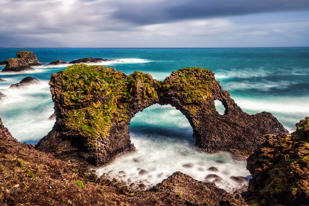 Incredibile arco di pietra Gatklettur roccia basaltica sulla costa atlantica di Arnarstapi in Islanda. Il famoso arco di forma naturale attrae i turisti da visitare nell'ovest dell'Islanda.