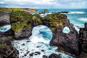 Amazing stone arch Gatklettur basalt rock on Atlantic coast of Arnarstapi in Iceland. The famous natural form arch attracts tourist to visit west of Iceland.