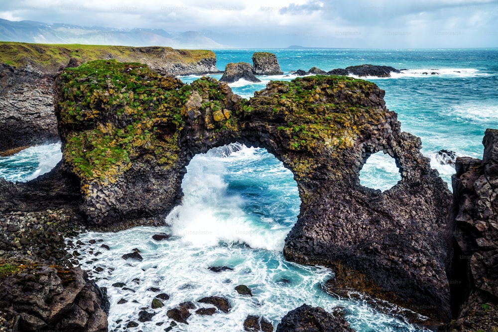 Incrível arco de pedra Gatklettur rocha basáltica na costa atlântica de Arnarstapi na Islândia. O famoso arco de forma natural atrai turistas para visitar o oeste da Islândia.