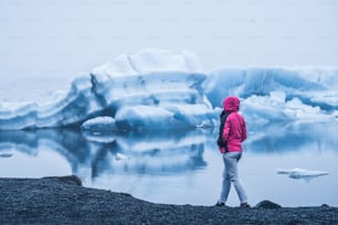 여성 여행자가 아이슬란드의 아름다운 빙하 석호인 요쿨살론으로 여행을 떠납니다. 요쿨살론은 유럽 아이슬란드 남동부의 바트나요쿨 국립공원에 있는 유명한 여행지입니다. 추운 겨울 얼음 자연.