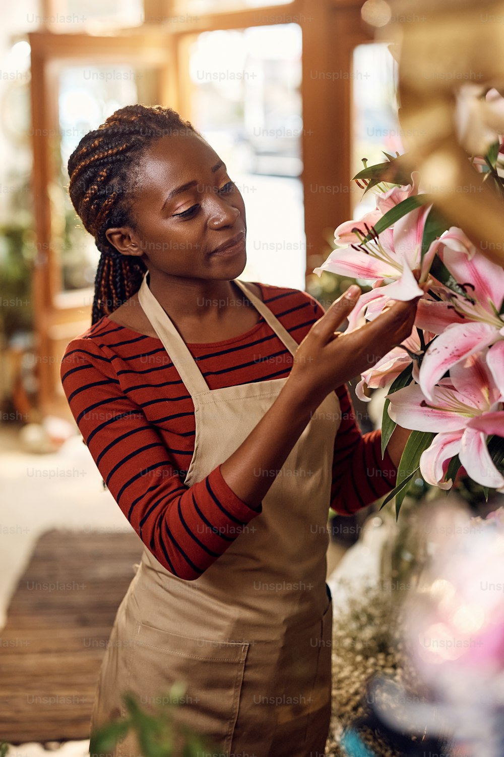 Glückliche afroamerikanische Frau, die es genießt, in ihrem Blumenladen zu arbeiten.