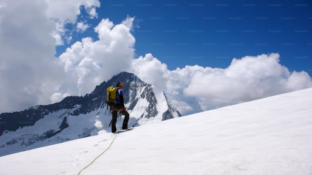 남성 산악인이 스위스 알프스의 높은 고산 빙하에 서서 정상과 목표를 바라보고 있습니다.