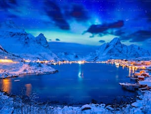 Aldeia Reine iluminada à noite com Aurora Boreal. Ilhas Lofoten, Noruega