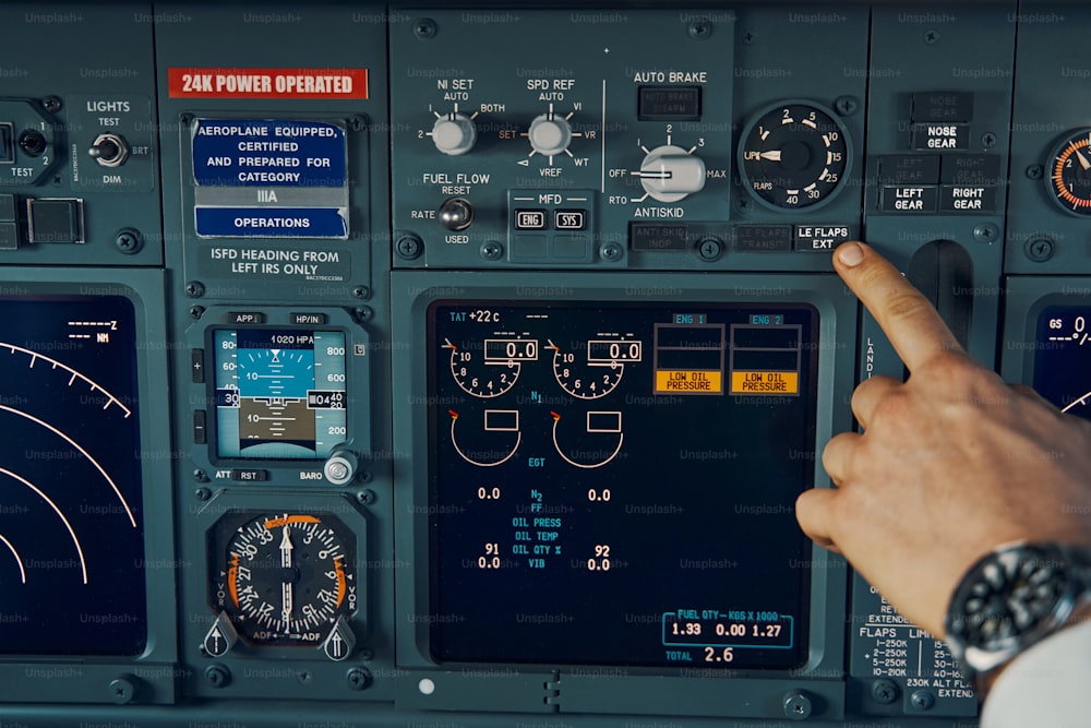 Foto recortada de uma mão do piloto pressionando o botão Leading Edge Flaps Extended no painel de instrumentos no convés de voo