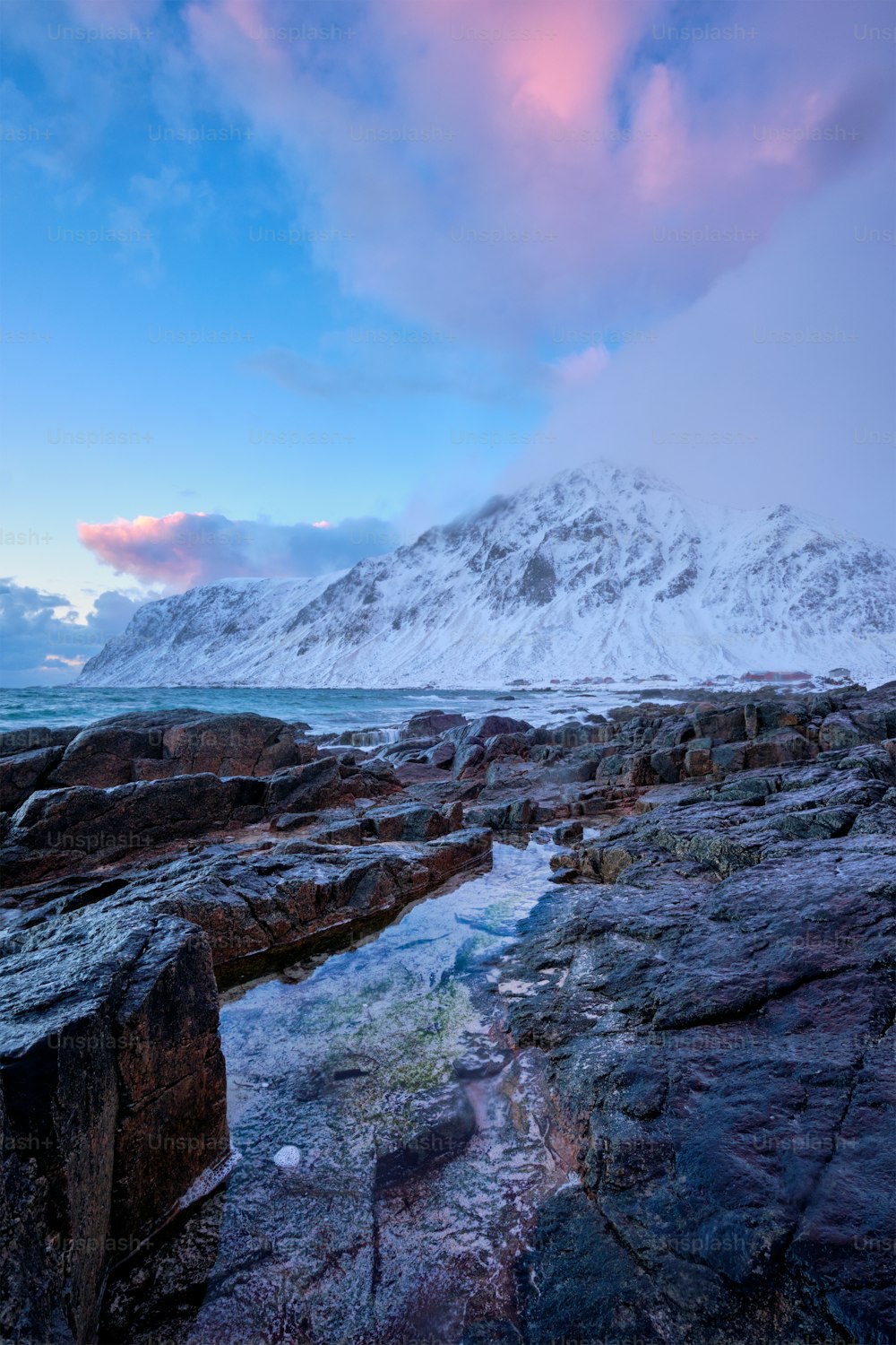 冬の夕暮れ時のフィヨルドの岩だらけの海岸にあるノルウェーの海のビーチ。ヴァレイド ビーチ、ロフォーテン諸島、ノルウェー
