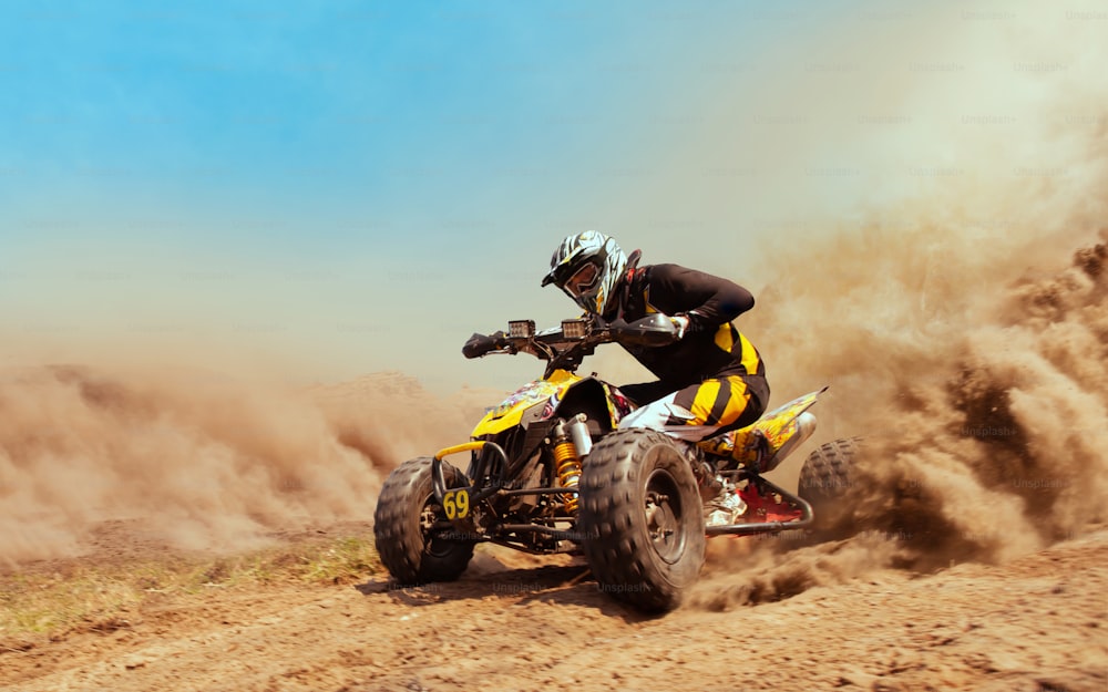 Quadriciclo na nuvem de poeira, pedreira de areia no fundo. ATV Rider na ação.