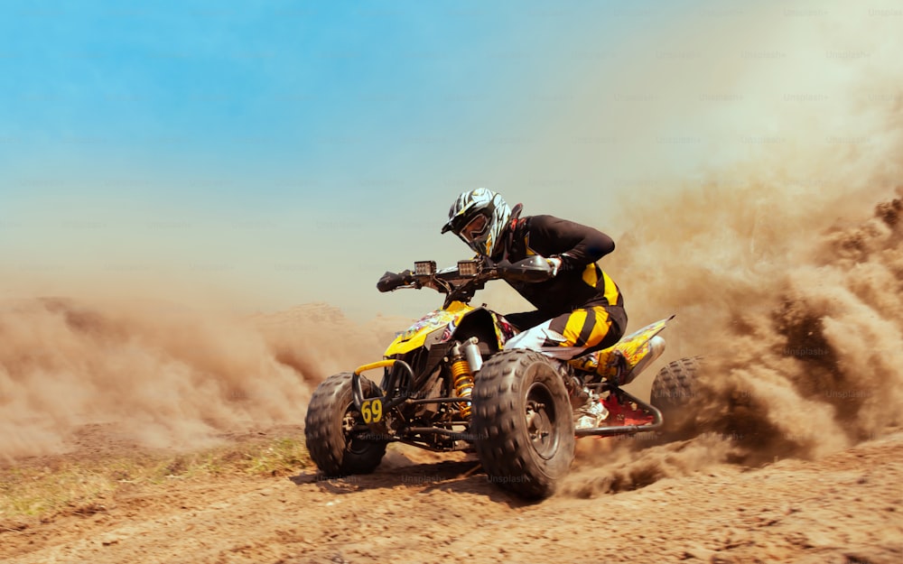 Quad bike in dust cloud, sand quarry on background. ATV Rider in the action.