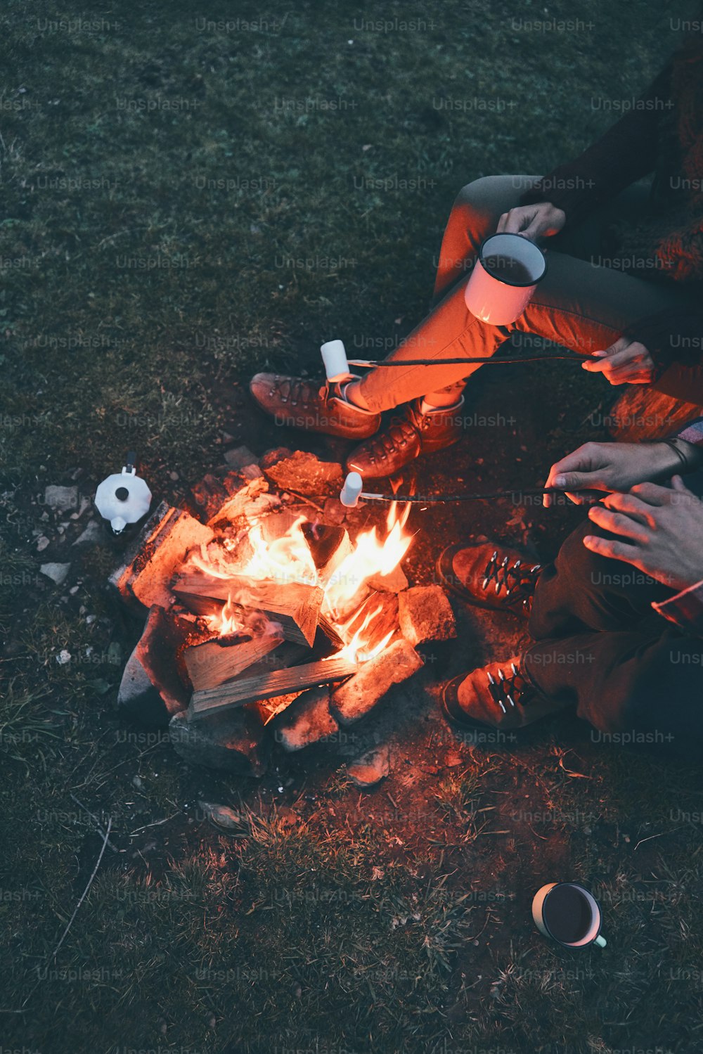 Close up top view of young couple roasting marshmallows over a campfire while camping in the mountains